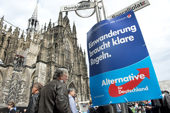 A placard reading "Immigration needs to be regulated in a clear way" hangs on a lamp post during an election rally of Germany's anti-Euro Alternative Fuer Deutschland (AFD - Alternative for Germany) Party, before the European Parlament elections, in front of Cologne's cathedral on April 26, 2014 (AFP Photo / John Macdougall)