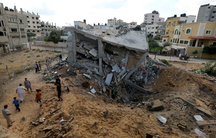 Palestinians gather around the remains of a house which police said was destroyed in an Israeli air strike in Gaza City July 14, 2014.(Reuters / Mohammed Salem )