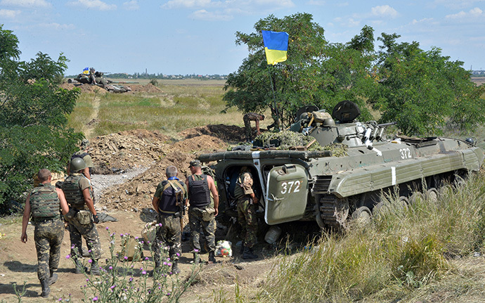 Ukrainian servicemen stand next to an armoured vehicle topped with a Ukrainian flag as they take up a position near the eastern city of Debaltceve, in the region of Donetsk (AFP Photo / Genya Savilov)