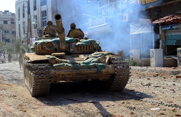 A handout picture released by the official Syrian Arab News Agency (SANA) on August 14, 2014, shows a Syrian army tank advancing in a street in Mleiha on the outskirts of the capital Damascus. (AFP Photo / SANA)