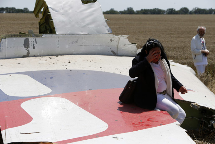 Angela Dyczynski sits on a piece of wreckage of Malaysia Airlines Flight MH17 near her husband Geaorge (R) during their visit to the crash site near the village of Hrabove (Grabovo), Donetsk region July 26, 2014. According to local media, Perth-based Dyczynski's daughter Fatima was aboard the Malaysia Airlines plane en route from Amsterdam to Kuala Lumpur when it was brought down in eastern Ukraine on July 17. (Reuters/Sergei Karpukhin)