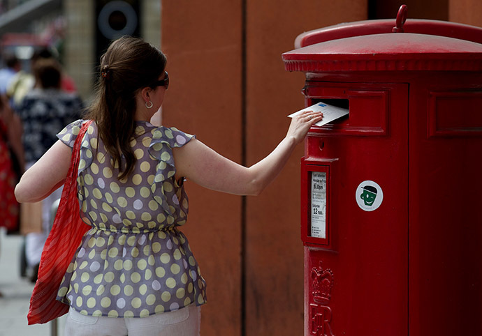 A woman posts a letter in a Royal Mail post box in London (AFP Photo / Andrew Cowie)