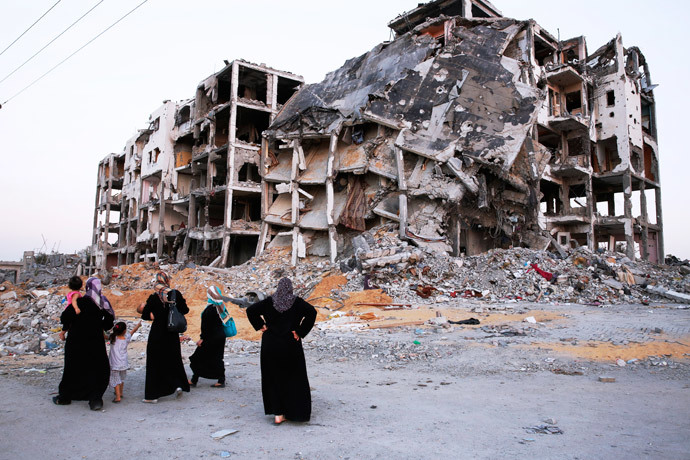 Palestinian women look at the shattered remains of a building complex that was destroyed by fighting between Hamas Militants and Israel on August 29, 2014 in the northern Gaza Strip city of Beit Hanun.(AFP Photo / Roberto Schmidt)