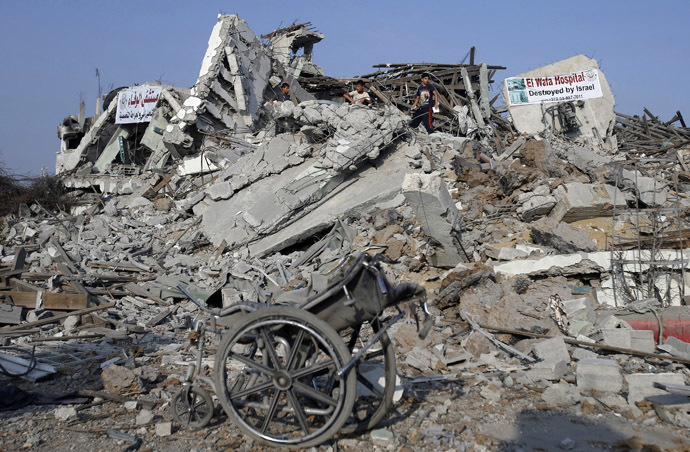 A wheelchair is seen as Palestinians stand atop the ruins of the headquarters of El-Wafa rehabilitation hospital, which witnesses said was destroyed during a seven-week Israeli offensive, in the east of Gaza City August 28, 2014. (Reuters)