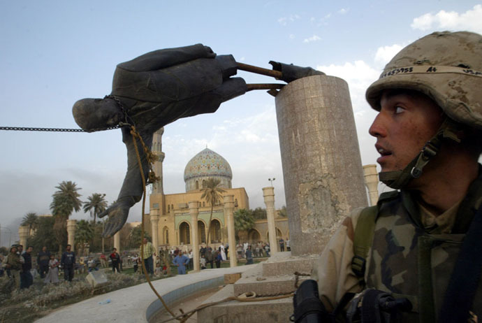 U.S. Marine Corp Assaultman Kirk Dalrymple watches as a statue of Iraq's President Saddam Hussein falls in central Baghdad April 9, 2003. (Reuters)