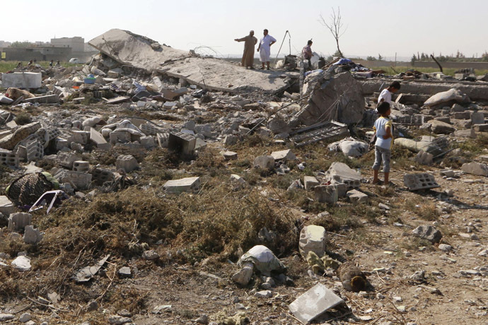People view the debris of their homes after a Syrian war plane crashed in Raqqa, in northeast Syria September 16, 2014. (Reuters/Stringer)