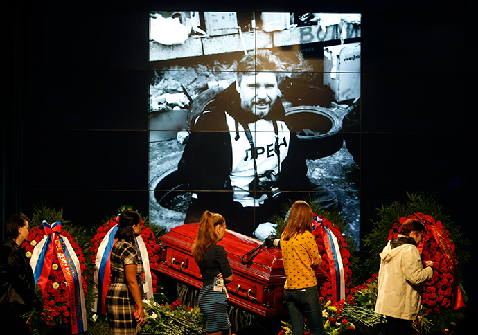 People walk past a coffin with the body of Russian photojournalist Andrey Stenin during a memorial service in Moscow, September 5, 2014 (Reuters / Sergey Karpukhin)
