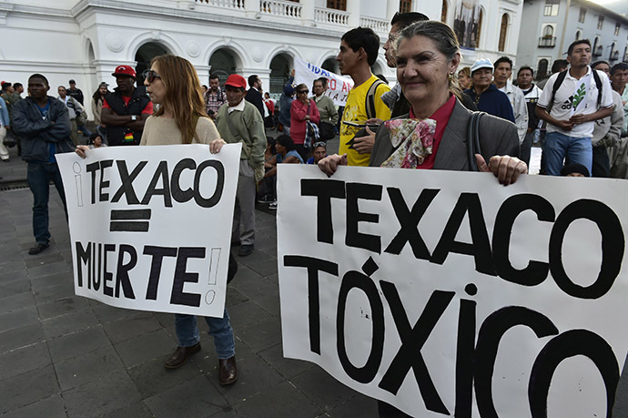 Activists holds signs reading "Texaco = Death" and "Texaco = Toxic" as they protest against US multinational energy corporation Chevron at a square in Quito on May 21, 2014. (AFP Photo/Rodrigo Buendia)