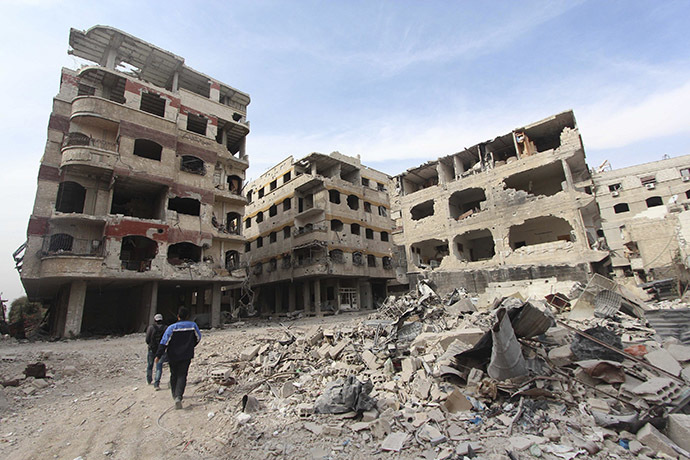 Civilians walk past damaged buildings in the Damascus suburb of Jobar October 28, 2014. (Reuters/Badra Mamet)