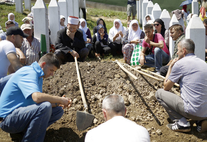 People sit around a grave during a burial at the Memorial Center Potocari, near Srebrenica, Bosnia and Herzegovina July 11, 2015. (Reuters/Stoyan Nenov)