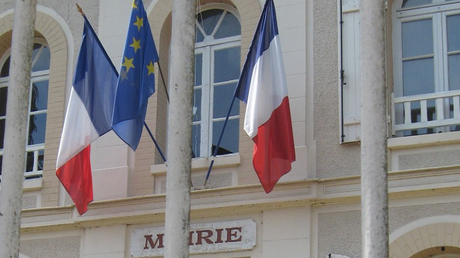 Le drapeau européen entouré de deux drapeaux français sur le fronton d'une mairie