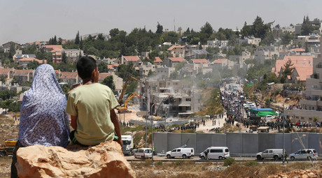 Des Palestiniens regardent les bulldozers israéliens dans la colonie juive de Cisjordanie de Beit El, près de Ramallah le 29 Juillet 2015.