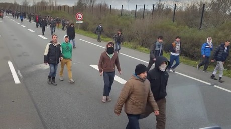 Des migrants sur l'autoroute menant au port de Calais essaie de grimper dans des camions