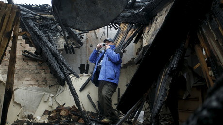 Un observateur de l'OSCE prend une photo d'une maison détruite à Donetsk