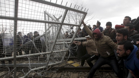 Des migrants tentent de faire tomber une partie de la barrière lors d'une manifestation à la frontière gréco-macédonienne le 29 février 2016