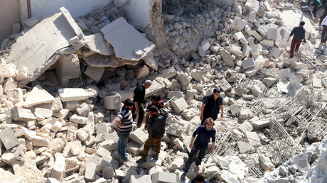 Des civils sur les ruines d'un bâtiment détruit par les bombardements aériens à Alep, le 16 avril 2016