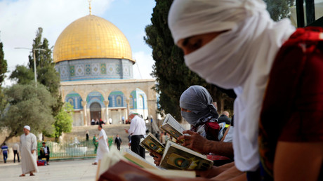 Des palestiniens masqués lisent le Coran près du Dôme du rocher, un lieu saint de l'Islam à Jerusalem