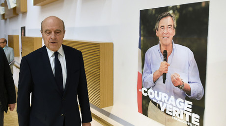 Alain Juppé passe devant une affiche de campagne de François Fillon pour assister au meeting de ce dernier à Bordeaux en février 2017.