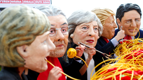 Des militants d'Oxfam arborant des masques à l'effigie des dirigeants des grandes puissances mondiales, en train d'avaler goulûment des plats de spaghettis. Taormine, Sicile, le 26 mai 2017. 