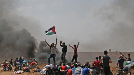 Des Palestiniens brandissent leur drapeau alors qu'ils manifestent près de la frontière entre Israël et la bande de Gaza, contre l'inauguration de l'ambassade des Etats-Unis après son transfert controversé à Jérusalem, le 14 mai 2018