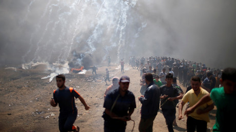 Des manifestants palestiniens sous les tirs de gaz lacrymogènes à la frontière entre Gaza et Israël, le 14 mai 2018