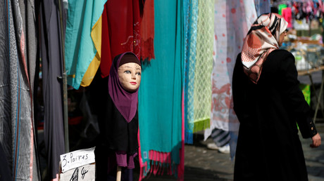Une femme passe devant un mannequin portant un foulard sur un marché du quartier bruxellois de Molenbeek 