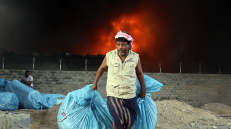 Un travailleur yéménite évacue des sacs de nourriture alors que le feu envahit l'entrepôt du Programme alimentaire mondial des Nations Unies (PAM) dans la ville côtière de Hodeidah le 31 mars 2018.