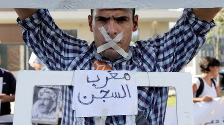Un proche des leaders du mouvement Hirak, portant une pancarte sur laquelle est écrite prison marocaine.