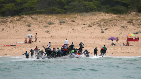 Des migrants débarquent d'un canot sur la plage 