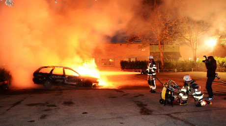 Des pompiers éteignant des voitures en feu lors des rixes de mai 2013  dans la banlieue de Stockholm en Suède/(Image d'illustration).