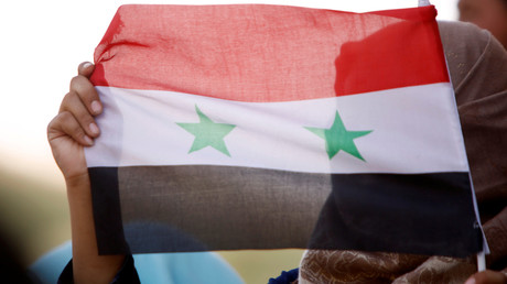 Un drapeau syrien brandi par une femme à Deraa.