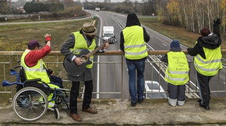 Des manifestants portant des gilets jaunes se tiennent sur un pont au-dessus de la route N70, le cinquième jour du mouvement contre la baisse du pouvoir d'achat et la hausse des prix, le 21 novembre 2018, près de Montceau-les-Mines, dans le centre de la France.