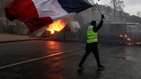 Un Gilet jaune brandit un drapeau tricolore devant une barricade à Paris, le 1er décembre.
