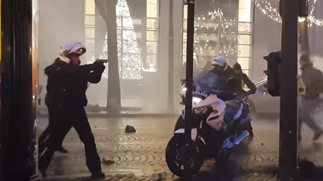 Un policier sort son arme pour maintenir des manifestants à distance lors de la mobilisation parisienne des Gilets jaunes, le 22 décembre 2018. 