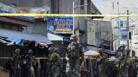 Des membres des forces de l'ordre devant l'église où deux bombes ont explosé, le 27 janvier 2019 à Jolo aux Philippines.