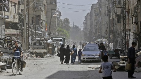 Des Syriens marchent dans une rue de Douma.