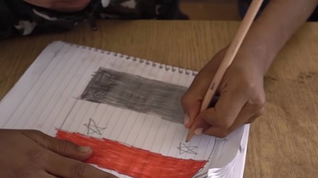 Un enfant syrien dessine le drapeau de son pays. 