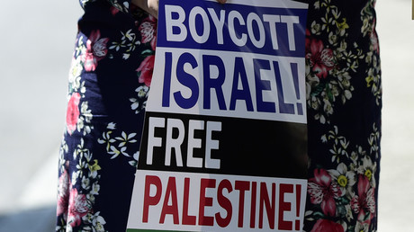 Jeune femme portant une pancarte incitant au boycott des produits israéliens (image d'illustration).