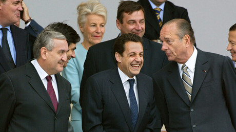 le président Jacques Chirac (D) s'adresse au ministre de l'Intérieur Nicolas Sarkozy (C) sous le regard du Premier ministre Jean-Pierre Raffarin (G), à la tribune officielle place de la Concorde à Paris, lors du traditionnel défilé militaire de célébration de la fête nationale.