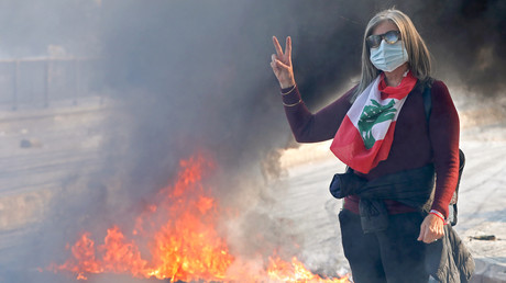 Une manifestante libanaise anti-gouvernement fait le signe de la victoire à côté d'un barrage routier en feu dans la capitale, Beyrouth, le 14 janvier 2020.