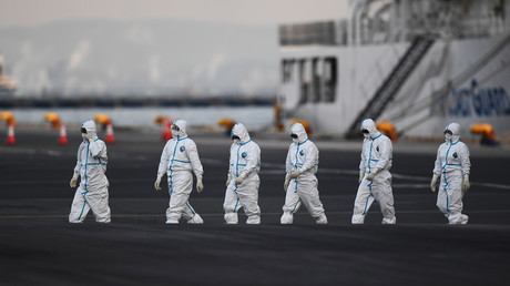 Des personnes portant des combinaisons de protection quittent le bateau de croisière Diamond Princess, avec environ 3 600 personnes mises en quarantaine à bord en raison des craintes du nouveau coronavirus, dans le port de Yokohama, au Japon, le 10 février 2020.