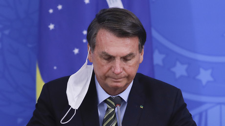 Jair Bolsonaro a vu son masque pendre à son oreille, en conférence de presse le 18 mars.