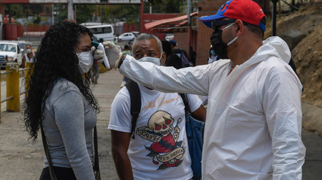 Un agent de santé vérifie la température d'une femme en dehors d'un marché municipal à titre de mesure préventive contre le nouveau coronavirus, COVID-19, à Caracas le 18 mars 2020.