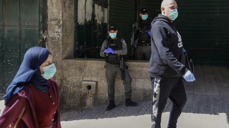 Les gardes-frontières israéliens regardent les Palestiniens passer, tous portant des masques de protection au milieu de l'épidémie de Covid-19, dans la vieille ville de Jérusalem, le 25 mars 2020.