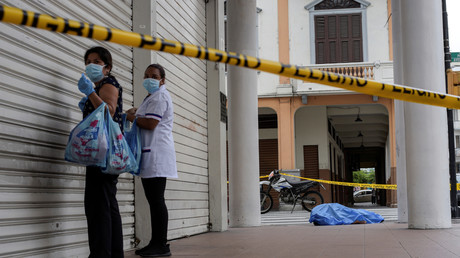 Des femmes se tiennent près du cadavre d'un homme qui s'était effondré sur le trottoir, lors de l'épidémie de coronavirus (Covid-19), à Guayaquil, Equateur, 30 mars 2020.