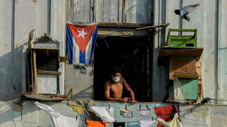 Un homme portant un masque de protection sur son balcon à La Havane