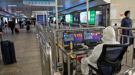 Un technicien contrôle la température des passants dans une gare de Wuhan.