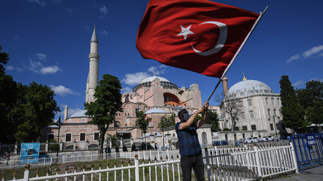 Un homme brandit un drapeau national turc alors que les gens se rassemblent à l'extérieur du musée de Sainte-Sophie le 10 juillet 2020 à Istanbul pour célébrer la révocation du statut de musée, transformant la basilique en mosquée.
