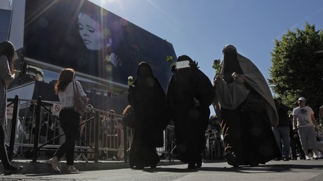 Trois femmes en voile intégral, dont l'une montre un chèque symbolisant l'amende qu'elle risque de payer en raison de la loi interdisant le port du voile intégral dans l'espace public en France ; photographie prise à Cannes en mai 2011 durant le festival (image d'illustration).
