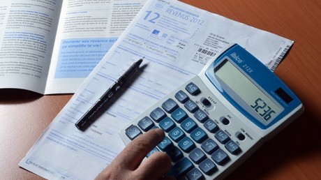 Une personne utilise une calculatrice pour remplir sa déclaration d'impôt sur le revenu, le 31 mars 2013 (image d'illustration).